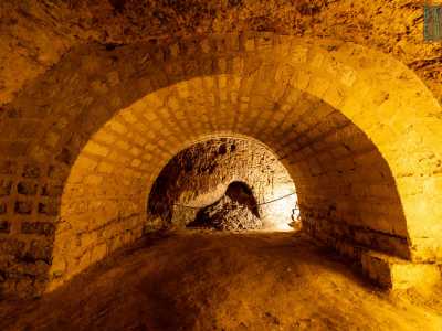 Superato il portale a destra si apre un primo ambiente, l�unico orientato in maniera obliqua rispetto ai tunnel. Al suo interno colpiscono subito delle massicce arcate in tufo che sostengono la volta